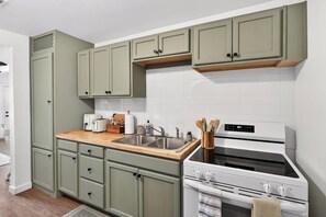 A kitchen with a white stove, a sink, and green cabinets. - Peaceful 2BR Home with Modern Comforts (Abilene)