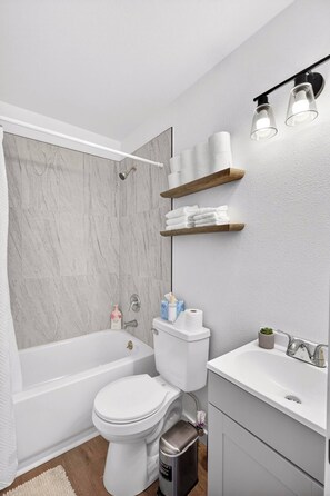 Une salle de bain moderne équipée d’une baignoire, de toilettes, d’un lavabo et d’un espace douche.