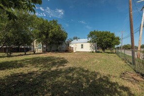 A residential property with a house, fenced yard, and trees. - Peaceful 2BR Home with Modern Comforts (Abilene)