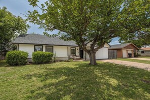 Ein eingeschossiges Haus mit Veranda, Garage und Baum im Vorgarten.