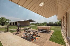 Une terrasse extérieure avec des tables de pique-nique, un barbecue et un espace salon abrité.
