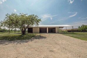 A building with a covered entrance and a gravel driveway. - Country Living: 3BR Hot Tub Escape: Close to all! (Abilene)