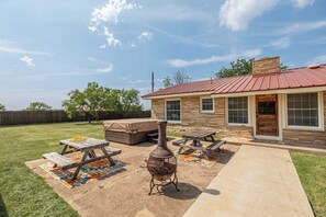 Patio trasero con una parrilla, mesa de picnic y zona de estar al aire libre.
