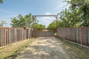 Un espacio exterior cercado con un sendero de grava que conduce a una entrada con portón.