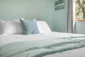 Een bed met wit beddengoed en een lichtblauwe plaid.