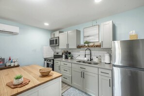 Een moderne keuken met roestvrijstalen apparatuur, witte kasten en een houten aanrecht.