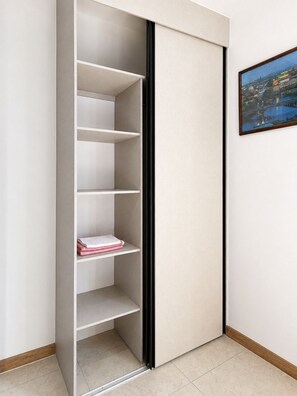 Een kast met meerdere planken, een schuifdeur en een lijst met een foto aan de muur.