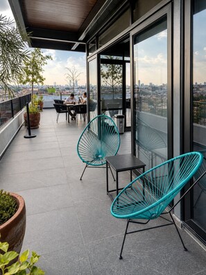 Een modern buitenzitgedeelte met stoelen en tafels, met uitzicht op een stadsgezicht.