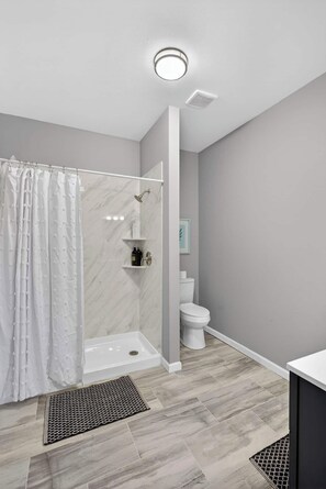 Un bagno moderno con doccia, WC e lavandino bianco.