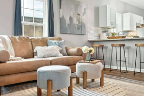 A modern living room with a leather sofa, a coffee table, and a bar area with stools. - NEW RENO! 4BR-2bath Modern Home | Central Location (Abilene)