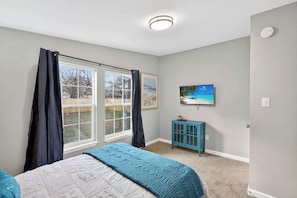 A bedroom with a bed, a television, a cabinet, and a window with curtains. - NEW RENO! 4BR-2bath Modern Home | Central Location (Abilene)