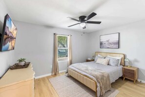 Une chambre à coucher comprenant un lit, une table de chevet, une commode et un ventilateur de plafond.