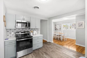 Una cocina moderna con armarios blancos, estufa de acero inoxidable y microondas.