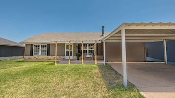 Een woonhuis met een overdekte patio, een garage en een verzorgd gazon.
