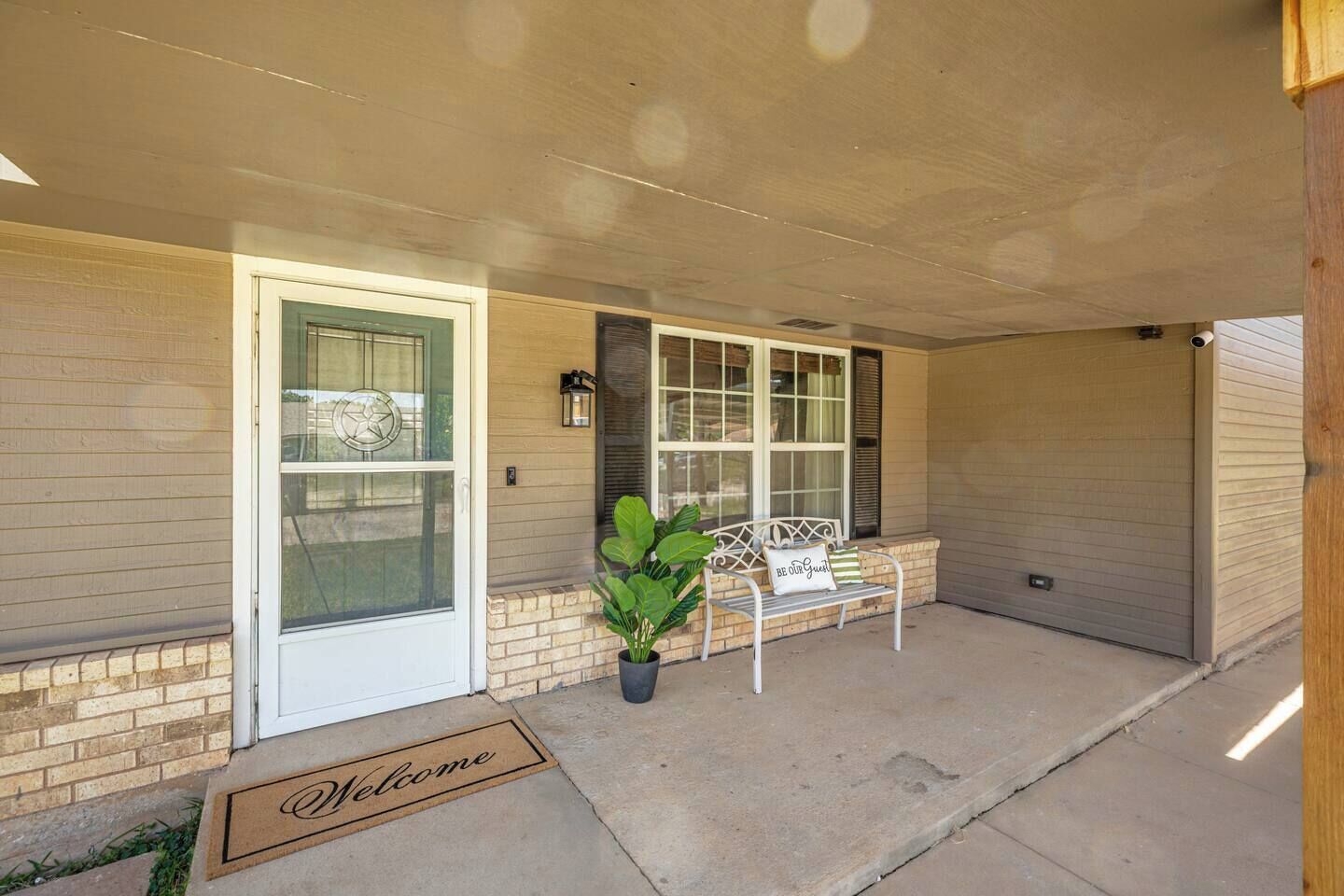 A residential entryway with a welcome mat, a bench, and a potted plant.