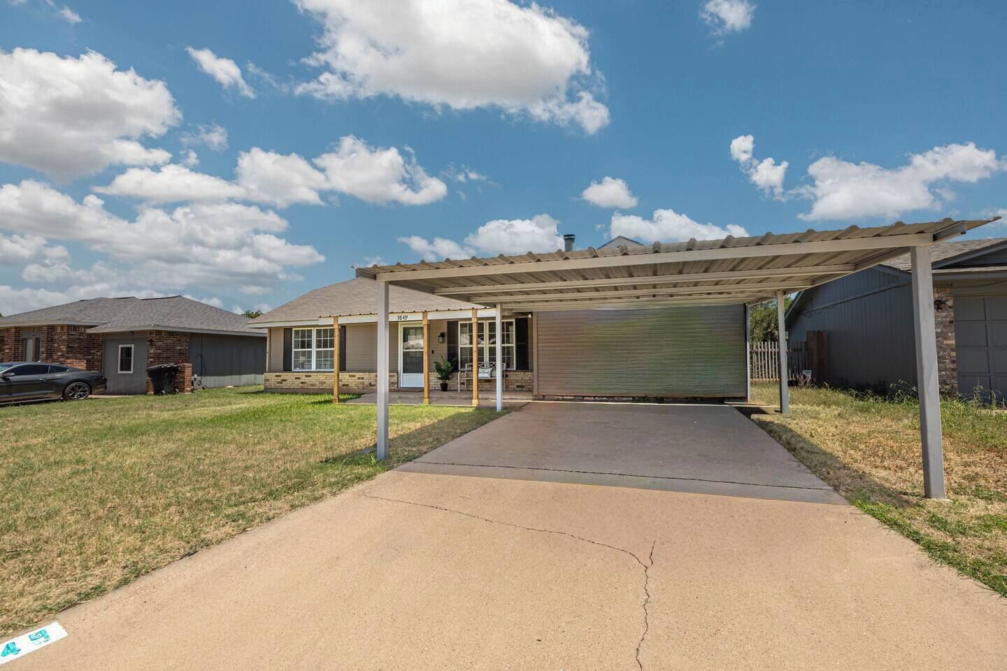 A residential property with a covered garage, a driveway, and a lawn.