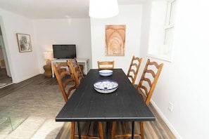 A dining area with a black table, wooden chairs, a bowl, and a painting on the wall. - Best Location in Wellington, Prince Edward County (Prince Edward)
