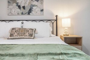 A neatly made bed with a green blanket, a decorative pillow, and a wall-mounted lamp beside it. - Cozy & Modern 3BR Home with Huge Backyard (Abilene)