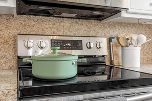 A kitchen with a stove, a pot on the burner, and a digital control panel. - Cozy & Modern 3BR Home with Huge Backyard (Abilene)