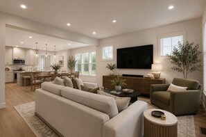 Ein modernes Wohnzimmer mit einer Couch, Sesseln, einem Couchtisch und einem Fernseher.