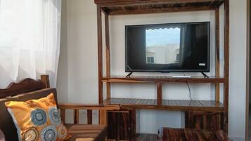 A living room with a wooden entertainment unit holding a flat-screen TV, a sofa with patterned cushions, and a coffee table.