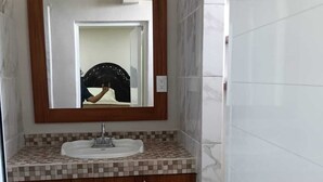 Ein Badezimmer mit Waschbecken, Spiegel und gefliesten Wänden.