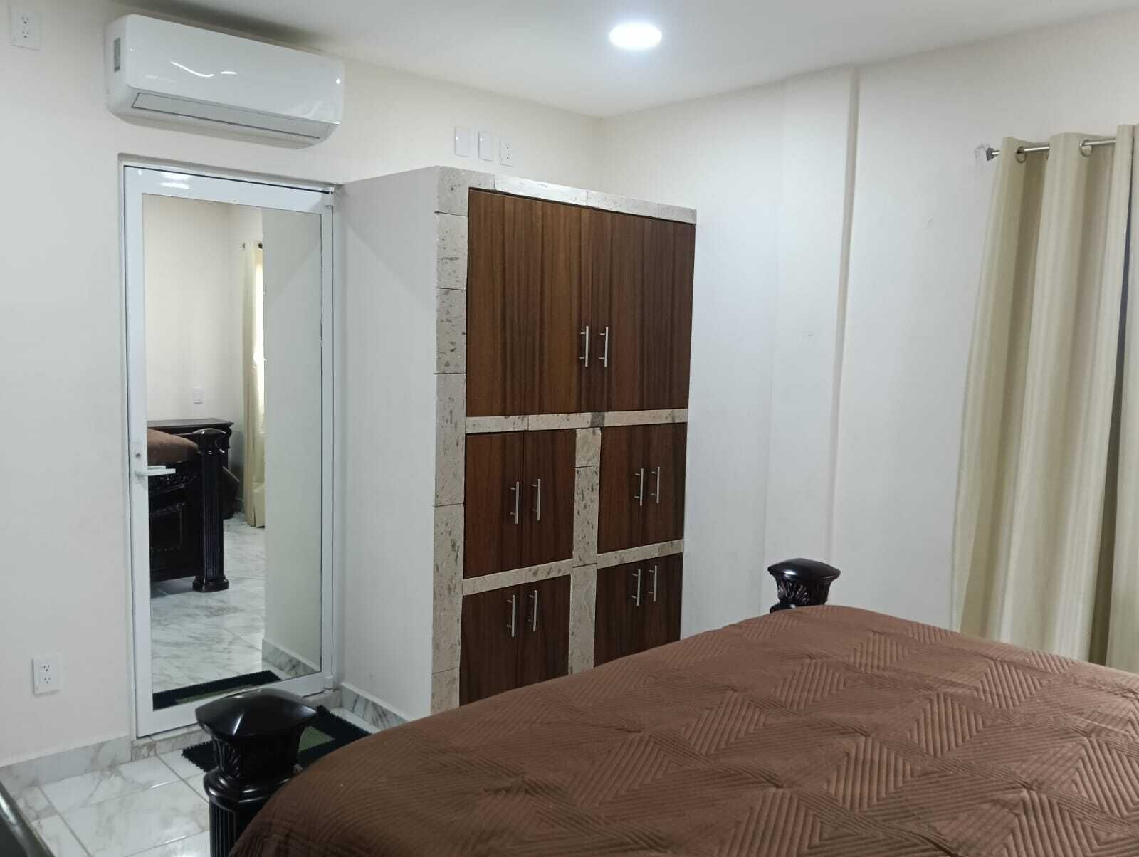 A bedroom with a bed, wardrobe, and a mirror.