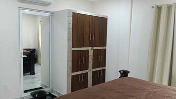 A bedroom with a bed, wardrobe, and a mirror.