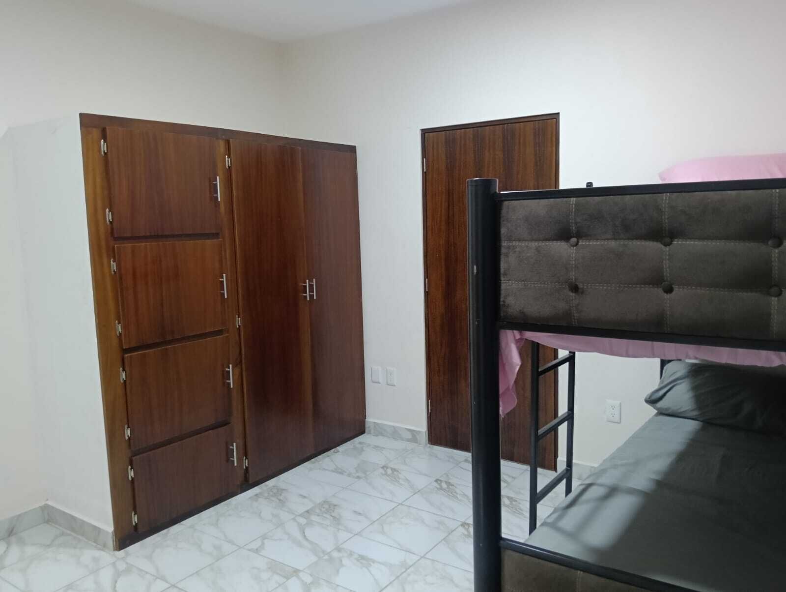 A room with a bunk bed, two wardrobes, and a tiled floor.