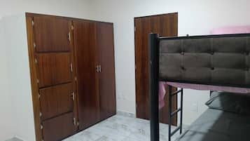 A room with a bunk bed, two wardrobes, and a tiled floor.