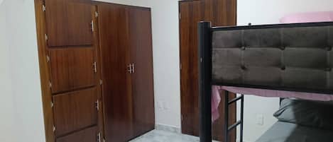A room with a bunk bed, two wardrobes, and a tiled floor.