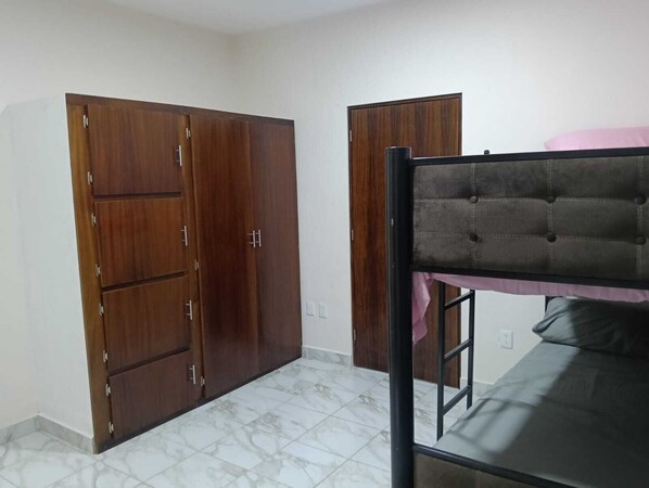 A room with a bunk bed, two wardrobes, and a tiled floor.