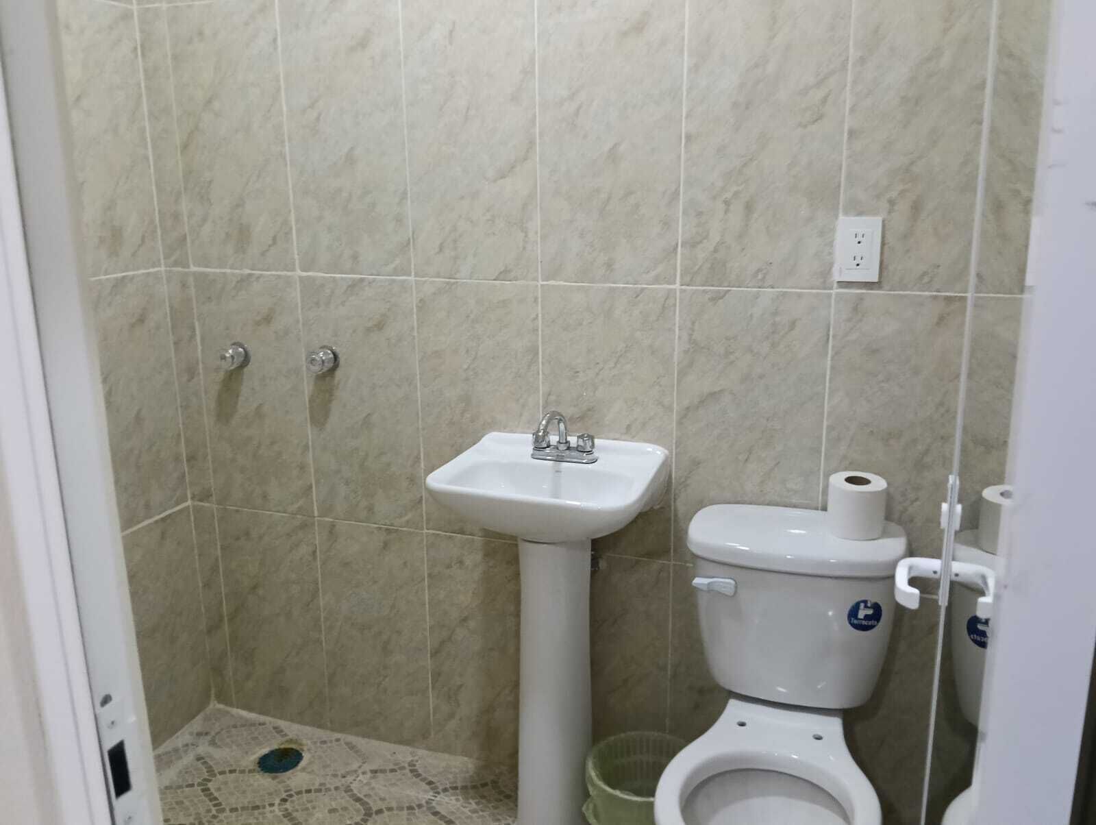 Un baño con lavamanos, inodoro y ducha blancos.