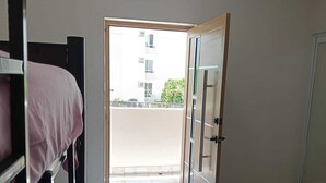 Ein Zimmer mit einem Etagenbett, einer Tür zu einem Balkon und einem Fliesenboden.