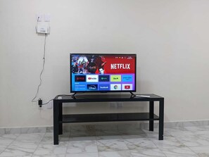 A television on a black stand with a visible power cord.