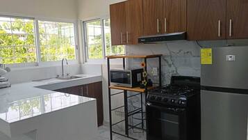 A modern kitchen with a central island, a stove, a microwave, and a refrigerator.