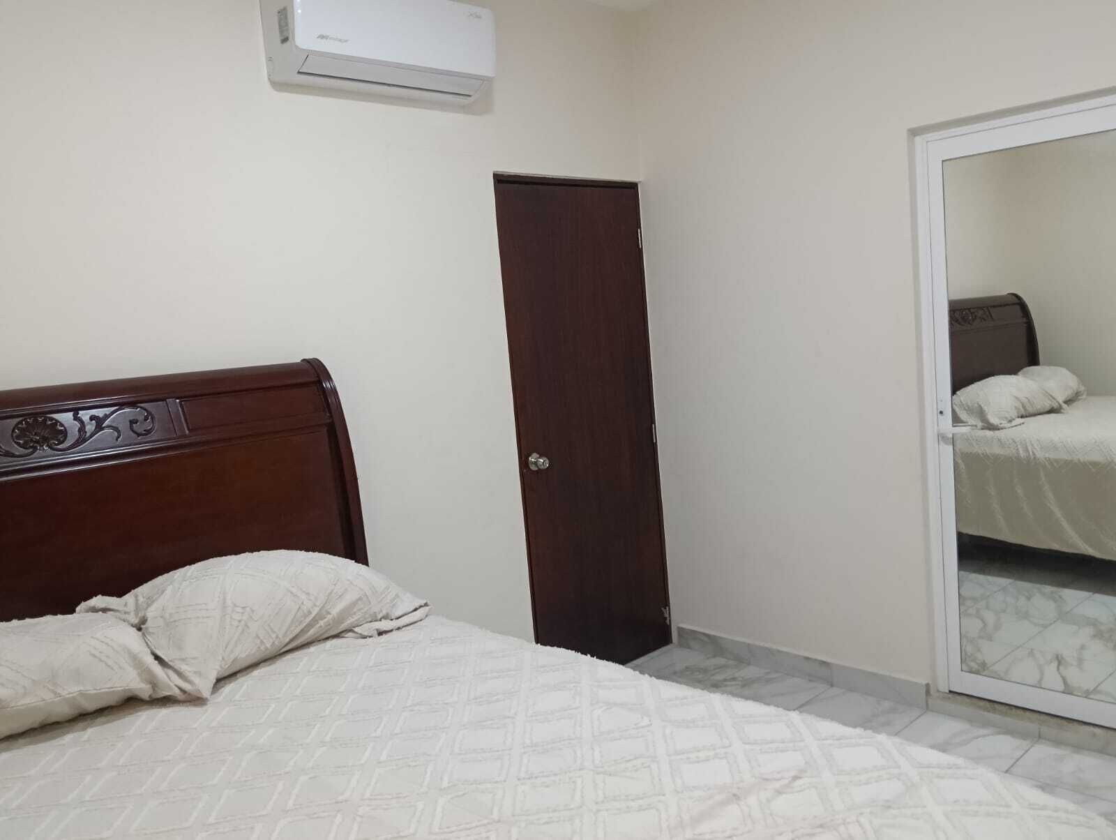 Een slaapkamer met een houten bed, een kledingkast en een deur naar een andere kamer.
