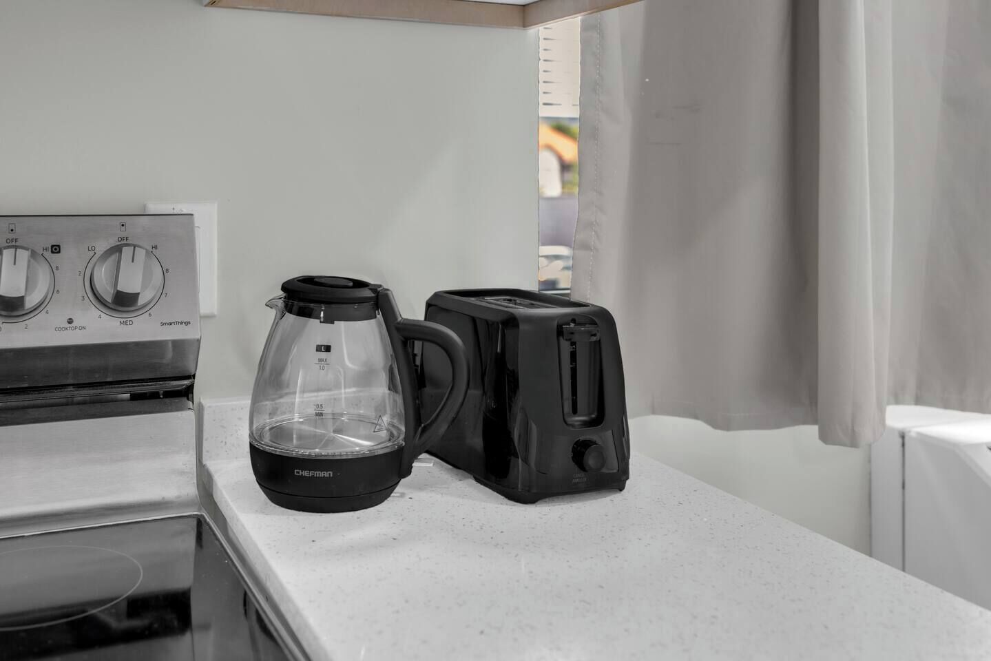 A kitchenette with a stove, a coffee maker, and a toaster on a white countertop.
