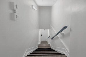 A staircase with wooden steps and a handrail, leading to a landing with a door.