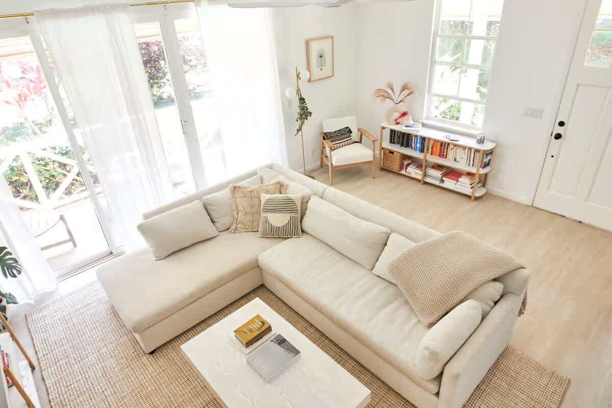 A living room with a beige sectional sofa, a coffee table, and a bookshelf.