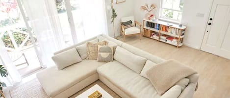 A living room with a beige sectional sofa, a coffee table, and a bookshelf.