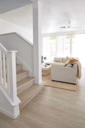 Eine Treppe führt zu einem Wohnbereich mit einem weißen Sofa und einem Couchtisch.