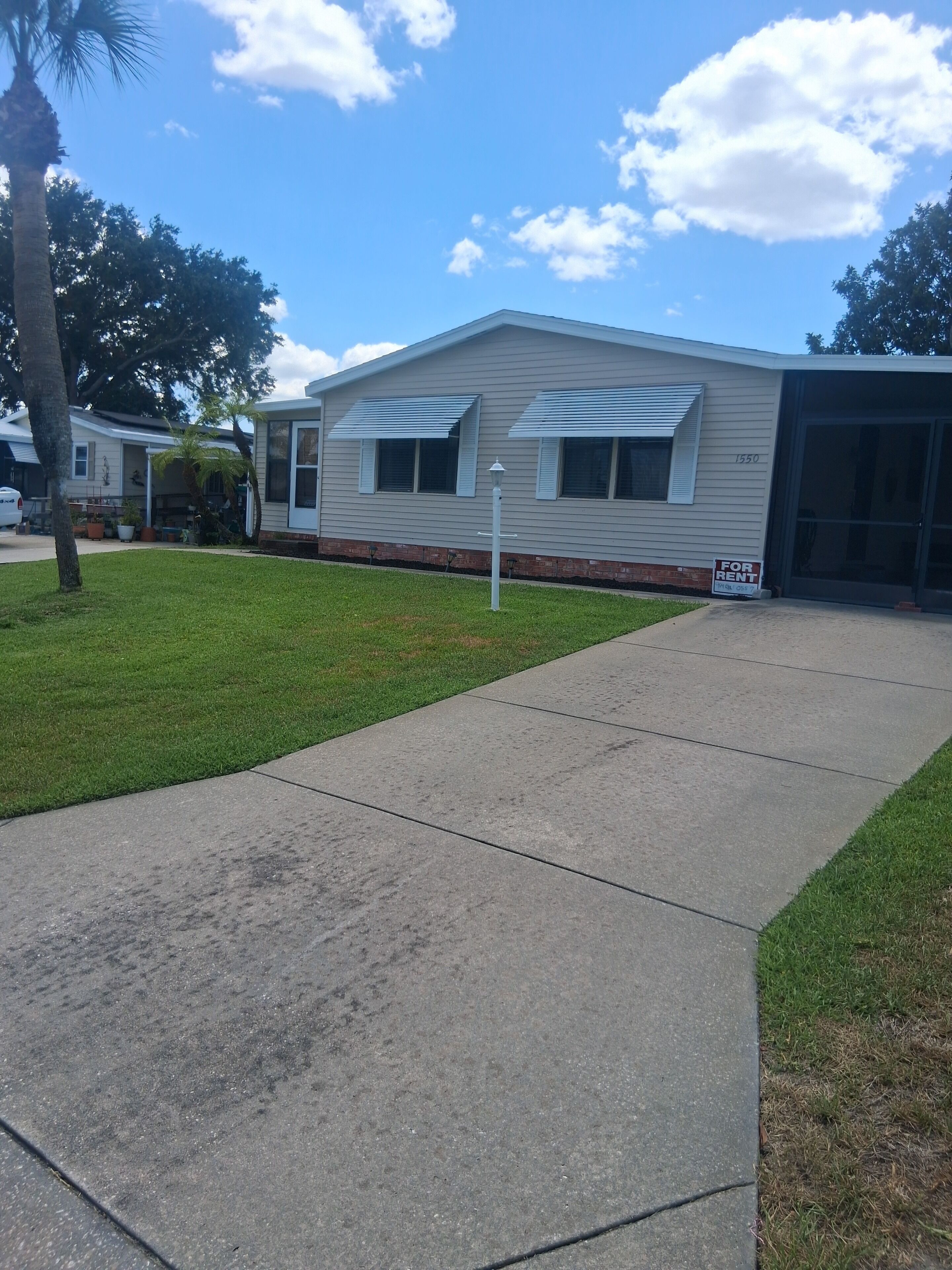 A single-story building with a garage door, a 'For Rent' sign, and a well-maintained lawn.