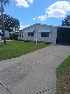 A single-story building with a garage door, a 'For Rent' sign, and a well-maintained lawn. - 2 Bedrooms 2 bathroom  in Villages within 5 minutes of  Walmart,UF Hospital (Lady Lake)