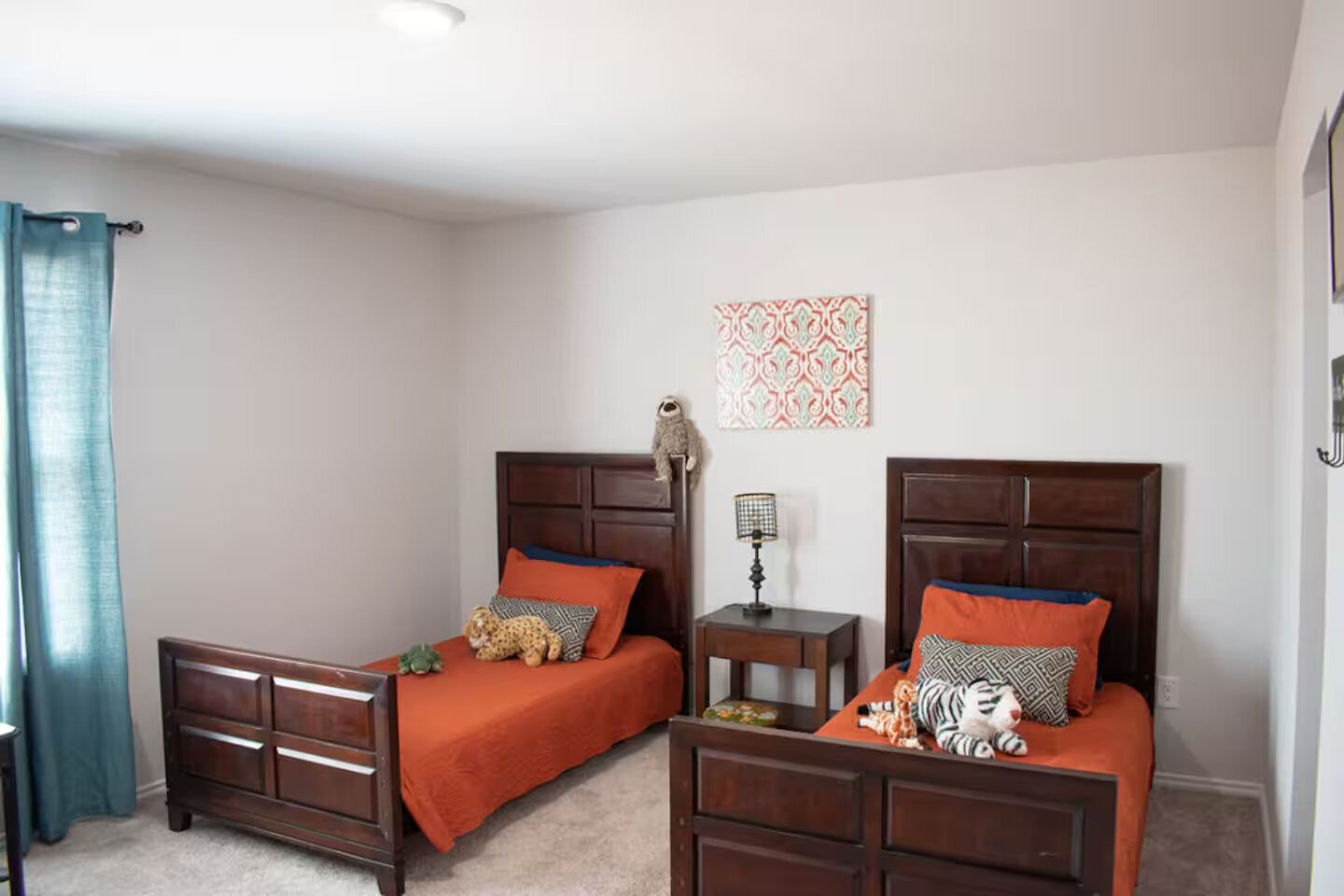 A bedroom with two wooden beds, each with a headboard, a small bedside table, and a lamp.