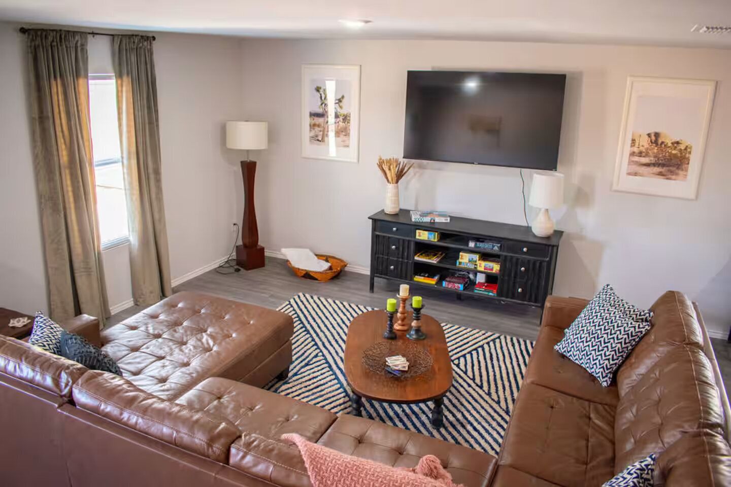 A living room with a brown leather sofa, a coffee table, a flat-screen TV, and a bookshelf.