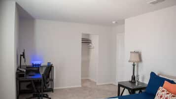 Een slaapkamer met een bed, een bureau met een computer, een lamp en een kast.