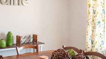 Een eethoek met een houten tafel, stoelen, een decoratieve schaal en een bord met een tekst aan de muur.