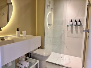 Een moderne badkamer met een douchecabine van glas, een wit wastafelmeubel met een marmeren blad en een toilet.
