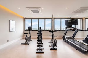 Een moderne sportschool met een loopband, een crosstrainer en een gewichtrek.